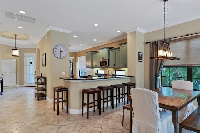 kitchen featuring pendant lighting, green cabinets, kitchen peninsula, and light tile patterned floors