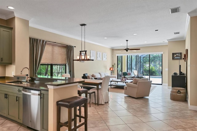 kitchen with hanging light fixtures, stainless steel dishwasher, green cabinetry, and crown molding