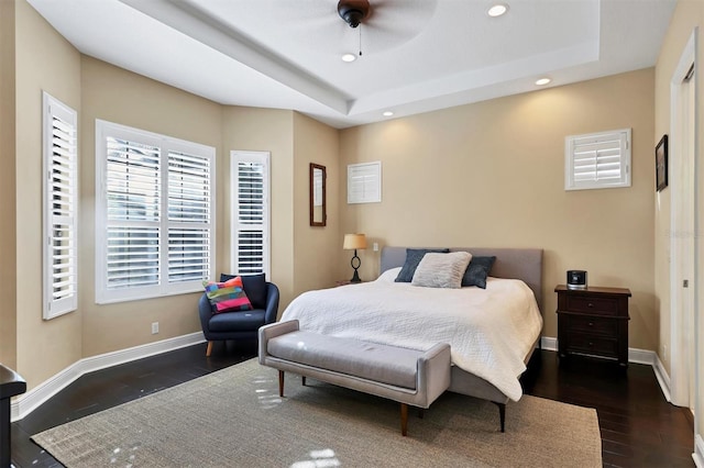 bedroom featuring ceiling fan, dark hardwood / wood-style floors, and a tray ceiling