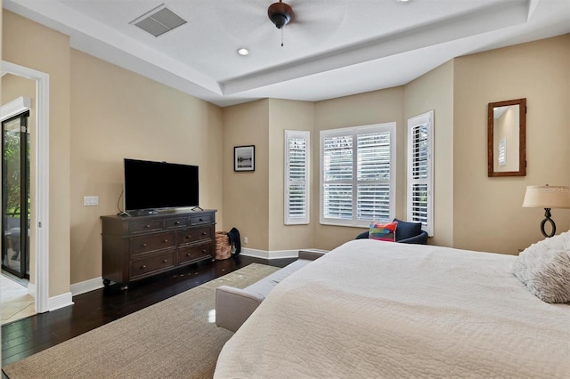 bedroom featuring a tray ceiling, access to exterior, ceiling fan, and dark wood-type flooring