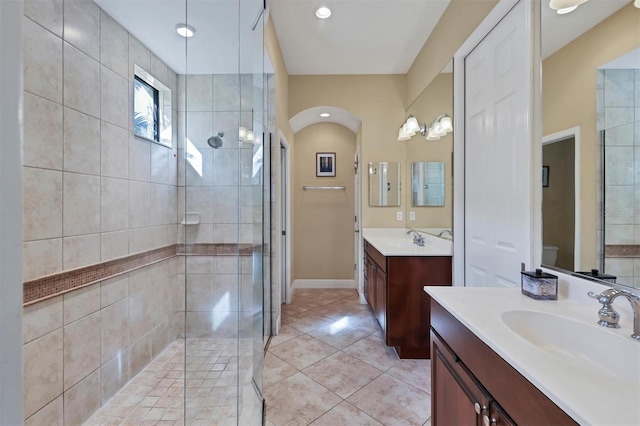 bathroom featuring toilet, vanity, tile patterned floors, and a shower with shower door