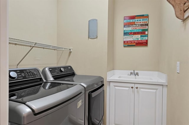 clothes washing area featuring cabinets, washer and clothes dryer, and sink