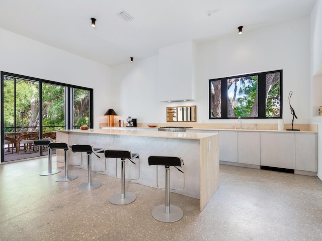 kitchen featuring a kitchen bar, white cabinetry, sink, and a center island