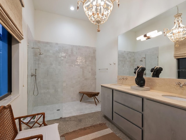 bathroom with vanity, a tile shower, and an inviting chandelier