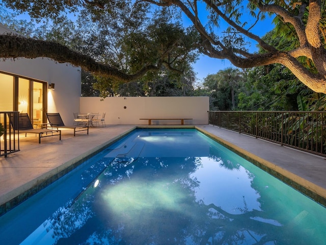 pool at dusk featuring a patio