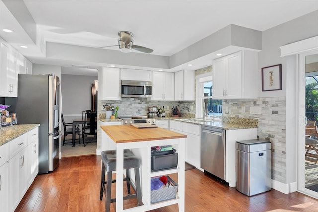 kitchen featuring a wealth of natural light, white cabinetry, stainless steel appliances, and wood-type flooring