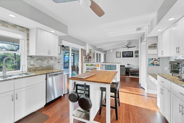 kitchen with white cabinets, sink, stainless steel dishwasher, dark hardwood / wood-style floors, and light stone countertops