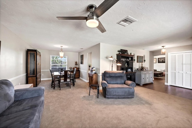 carpeted living room with ceiling fan and a textured ceiling