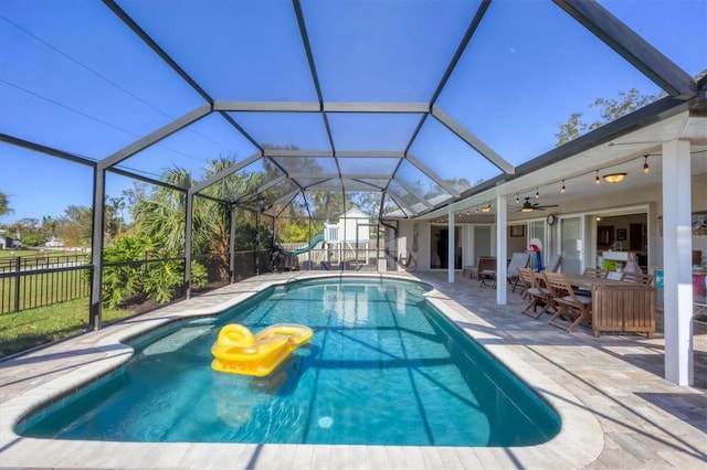 view of swimming pool featuring ceiling fan, a patio area, and glass enclosure