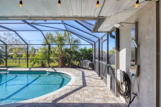 view of pool featuring glass enclosure and a patio area