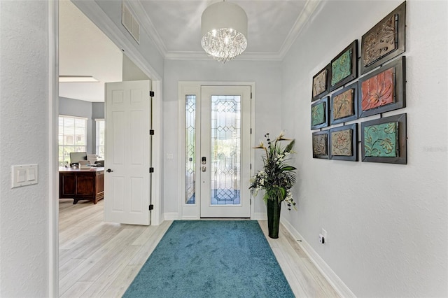 foyer entrance featuring a chandelier, light hardwood / wood-style flooring, and ornamental molding