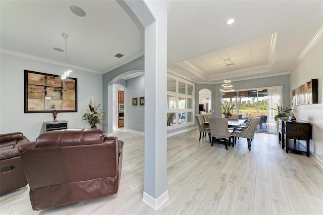 dining area with ornamental molding, light wood-type flooring, and a tray ceiling