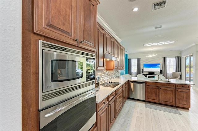 kitchen featuring sink, appliances with stainless steel finishes, kitchen peninsula, crown molding, and light wood-type flooring