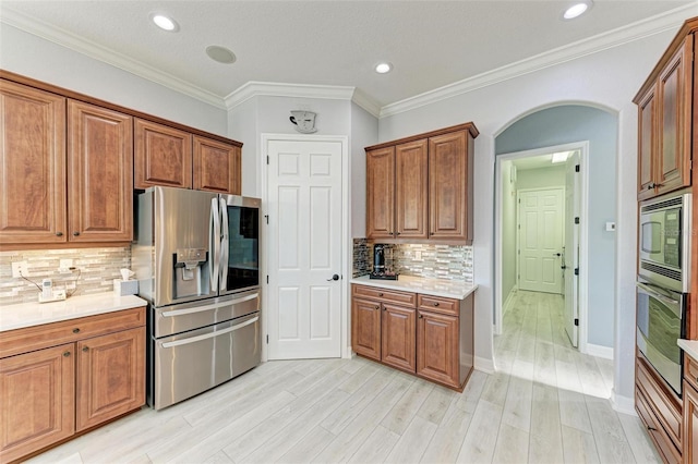 kitchen with light hardwood / wood-style flooring, decorative backsplash, ornamental molding, and stainless steel appliances