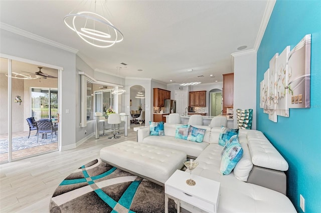 living room featuring light wood-type flooring, crown molding, and ceiling fan with notable chandelier