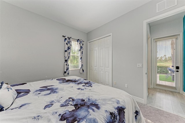 bedroom with wood-type flooring, multiple windows, and a closet