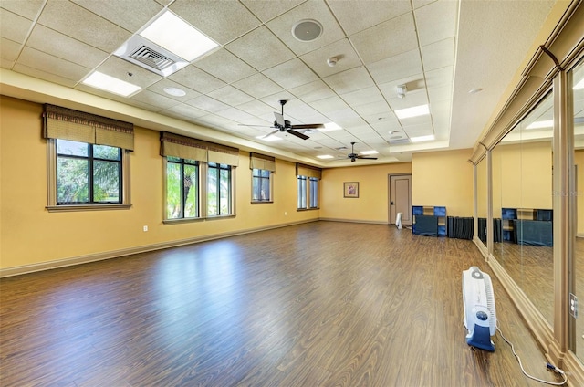 exercise room featuring dark wood-type flooring, a paneled ceiling, and ceiling fan