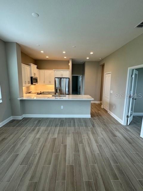 kitchen featuring kitchen peninsula, white cabinets, wood-type flooring, and stainless steel appliances