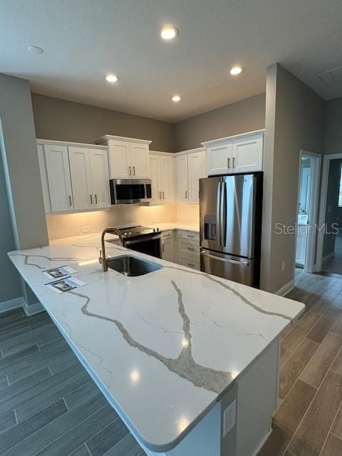 kitchen featuring white cabinetry, appliances with stainless steel finishes, sink, dark wood-type flooring, and kitchen peninsula