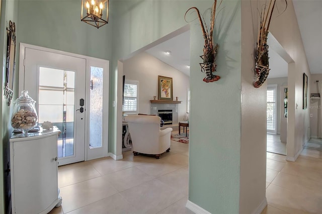 entryway with a notable chandelier, lofted ceiling, and light tile patterned floors