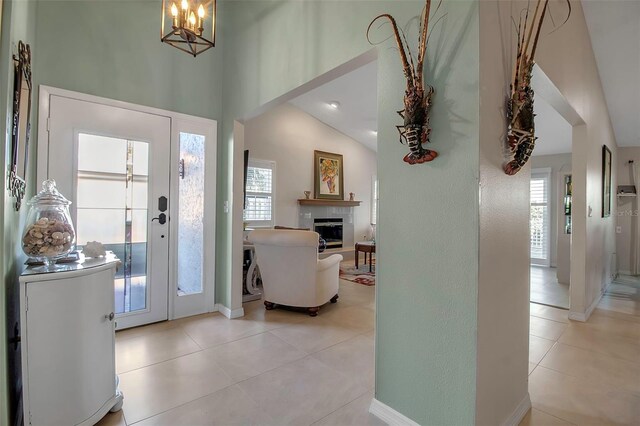 3410 Avenida Madera Unit B, Bradenton, FL 34210 - foyer entrance with a fireplace, light tile patterned flooring, a chandelier, baseboards, and vaulted ceiling