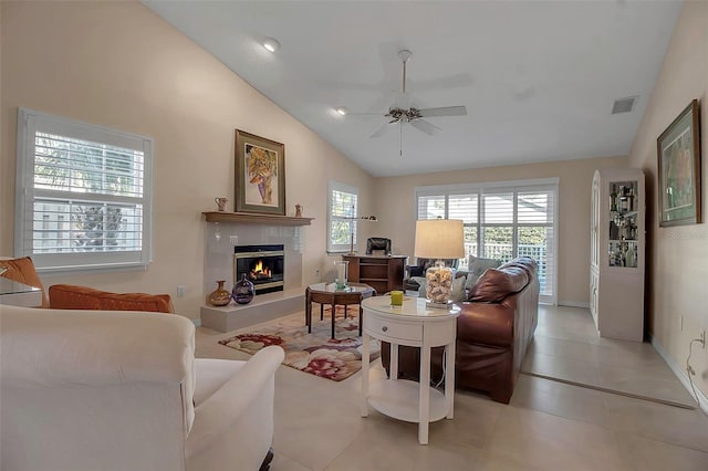 living room featuring high vaulted ceiling, ceiling fan, a healthy amount of sunlight, and a tiled fireplace