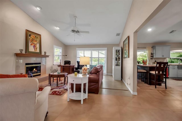 tiled living room with a fireplace, vaulted ceiling, and ceiling fan