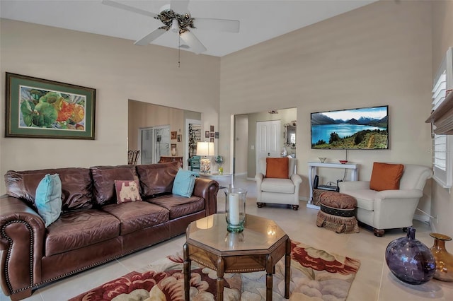 tiled living room featuring ceiling fan and a high ceiling