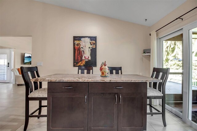 3410 Avenida Madera Unit B, Bradenton, FL 34210 - kitchen featuring a breakfast bar, dark brown cabinets, lofted ceiling, light countertops, and light tile patterned floors