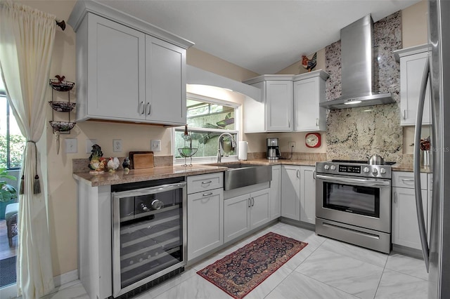 kitchen with appliances with stainless steel finishes, sink, wall chimney range hood, white cabinets, and wine cooler