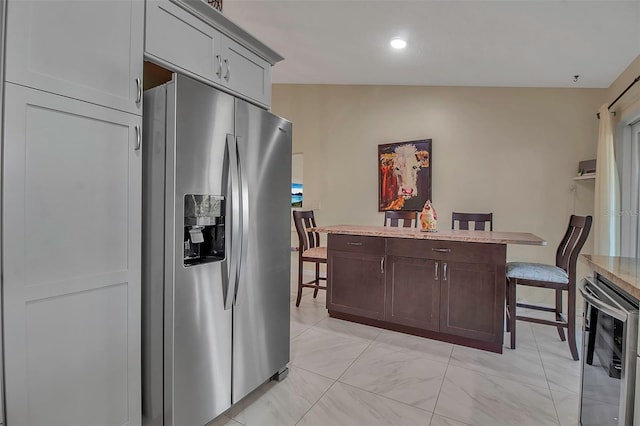 kitchen featuring stainless steel refrigerator with ice dispenser, dark brown cabinets, beverage cooler, gray cabinets, and lofted ceiling