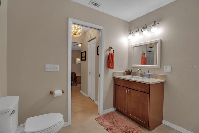 bathroom with tile patterned flooring, vanity, toilet, and an inviting chandelier