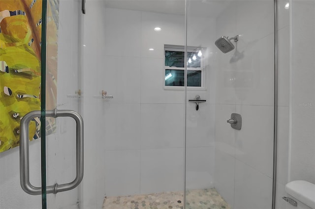 bathroom with a shower with door and toilet