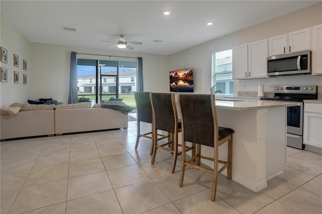 kitchen with white cabinetry, appliances with stainless steel finishes, a healthy amount of sunlight, and a breakfast bar