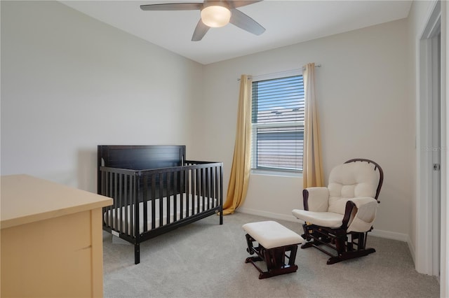 bedroom with a nursery area, ceiling fan, and light colored carpet