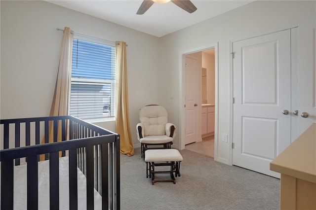 carpeted bedroom with connected bathroom, ceiling fan, and a crib