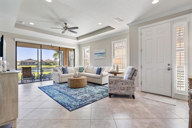 tiled living room with plenty of natural light, a textured ceiling, and a tray ceiling