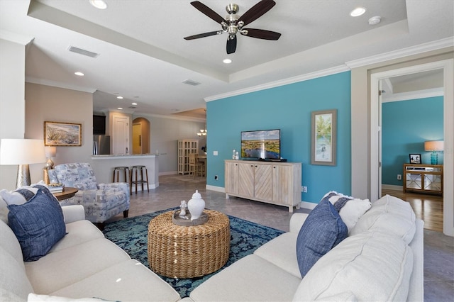 living room featuring tile patterned floors, ceiling fan, a raised ceiling, and ornamental molding