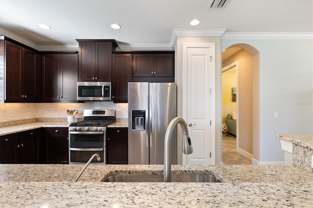 kitchen featuring decorative backsplash, appliances with stainless steel finishes, dark brown cabinetry, and sink