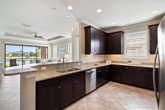 kitchen with sink, kitchen peninsula, decorative backsplash, appliances with stainless steel finishes, and ornamental molding