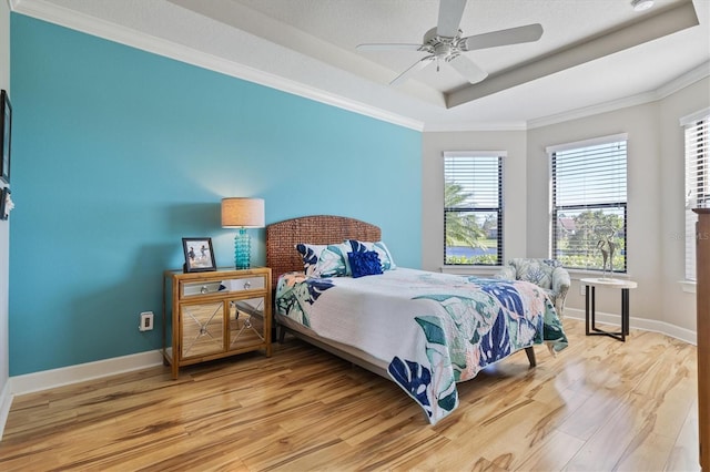 bedroom featuring a tray ceiling, ceiling fan, ornamental molding, and hardwood / wood-style flooring