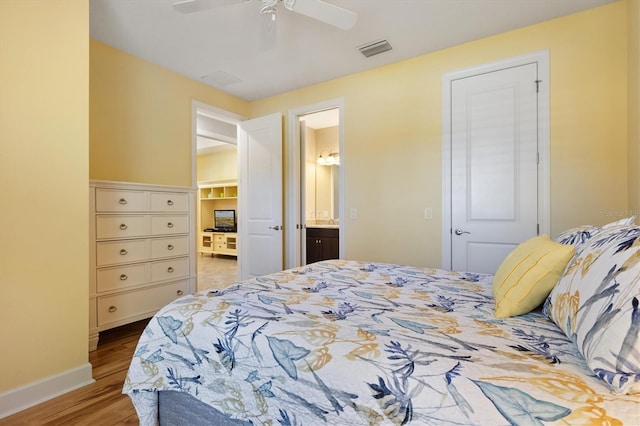 bedroom featuring hardwood / wood-style floors, ceiling fan, and ensuite bath