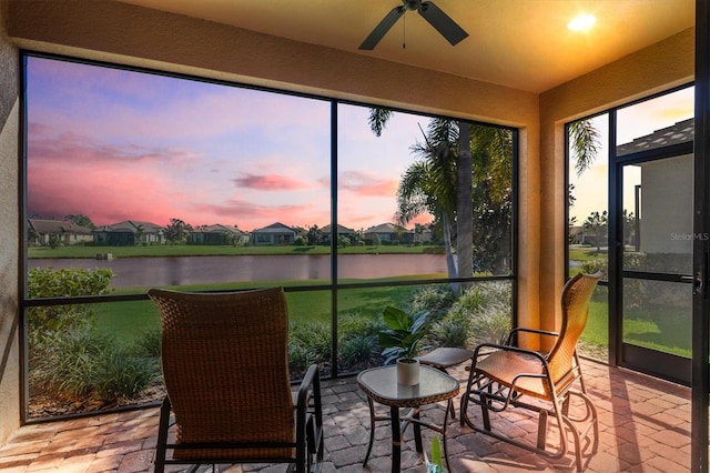 sunroom / solarium featuring ceiling fan and a water view