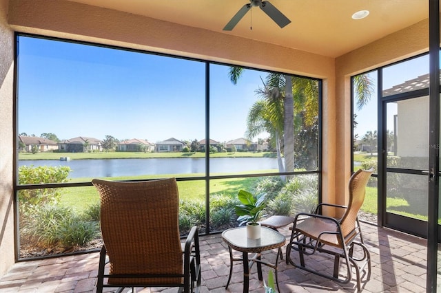 sunroom / solarium featuring ceiling fan and a water view