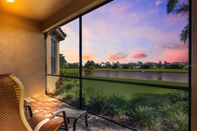 sunroom featuring a water view