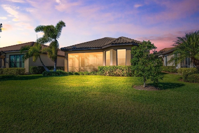 property exterior at dusk featuring a lawn