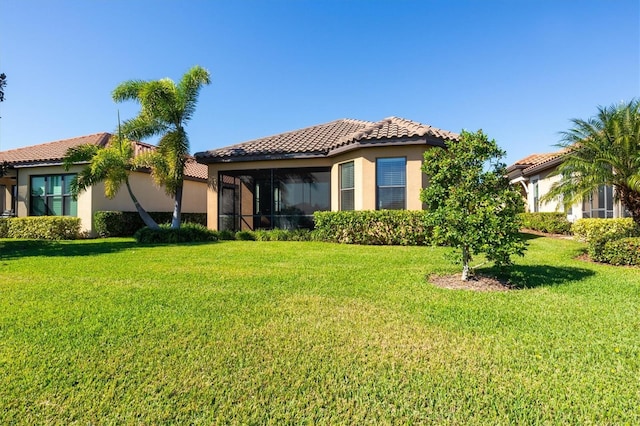 rear view of property featuring a sunroom and a lawn