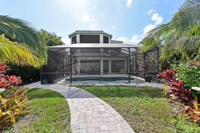 rear view of house with a yard and glass enclosure