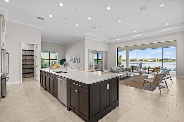 kitchen featuring a center island with sink, sink, ornamental molding, appliances with stainless steel finishes, and dark brown cabinets