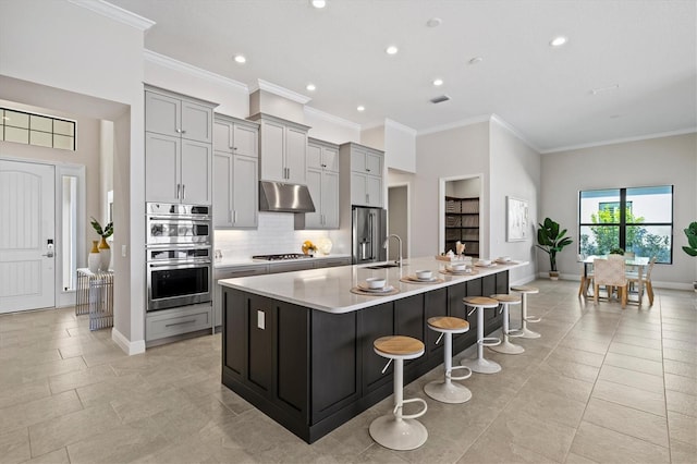 kitchen featuring a breakfast bar area, a large island with sink, gray cabinetry, and stainless steel appliances